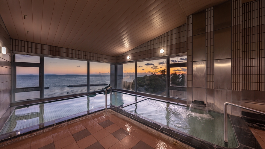 【大浴場－男湯】二面に広がる窓から、美しい朝陽がご覧いただけます。