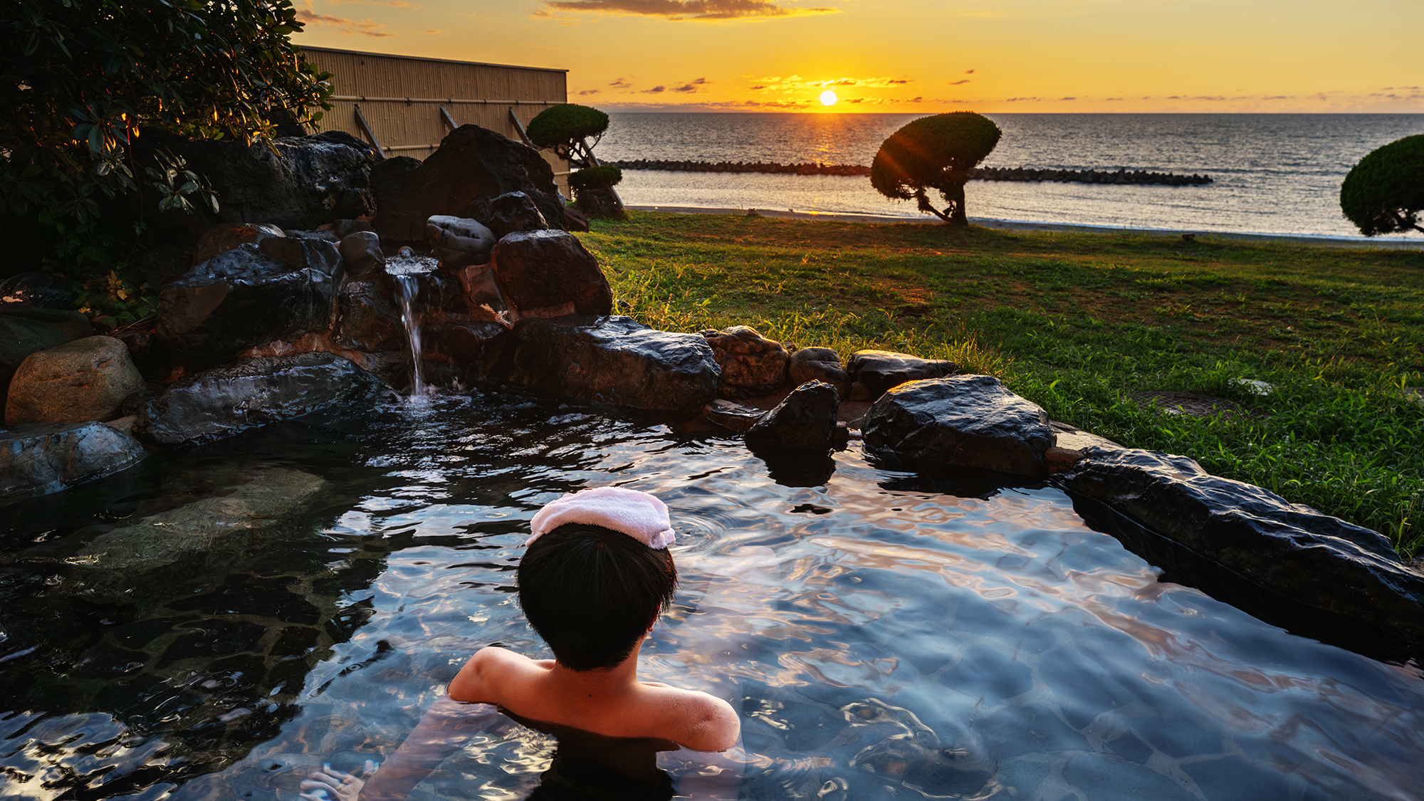 【露天風呂】波打ち際のすぐそば、露天風呂から望む夕暮れの海。心地よい潮風と温泉で至福のバスタイム。