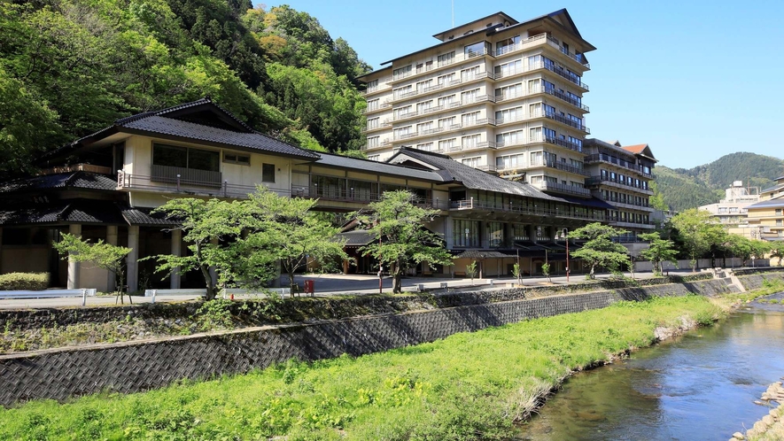 【萬国屋の全景】温海川沿いの緑豊かな立地