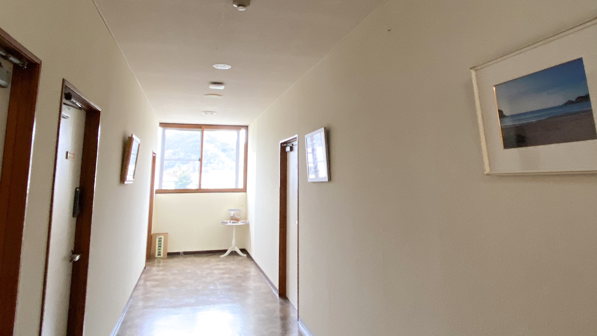 ・【館内】海の写真が飾られた廊下の先に広がる客室エリア