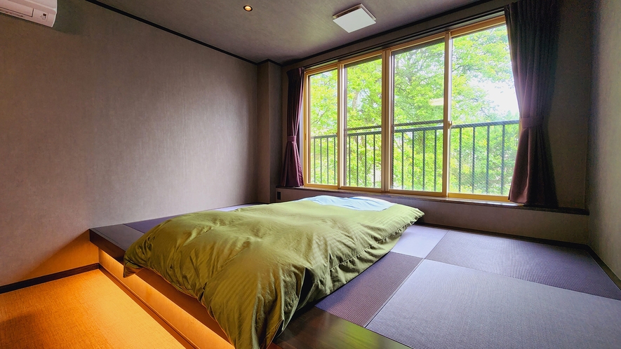＃和洋室-13～14畳-　畳の小上がりにローベッドの和洋室。窓から優しい陽光が客室内を照らします。