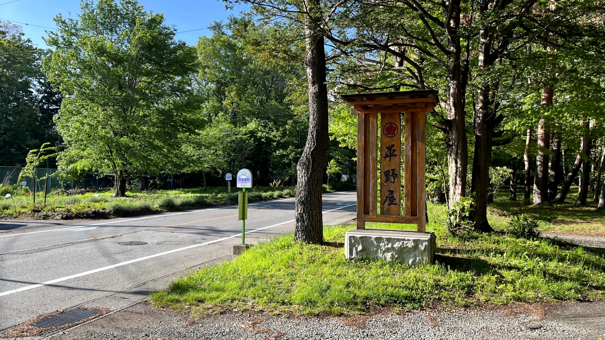 *当館入口／当館の看板が木の影に隠れ、見えづらくなっております。バス停を目印にお越しください