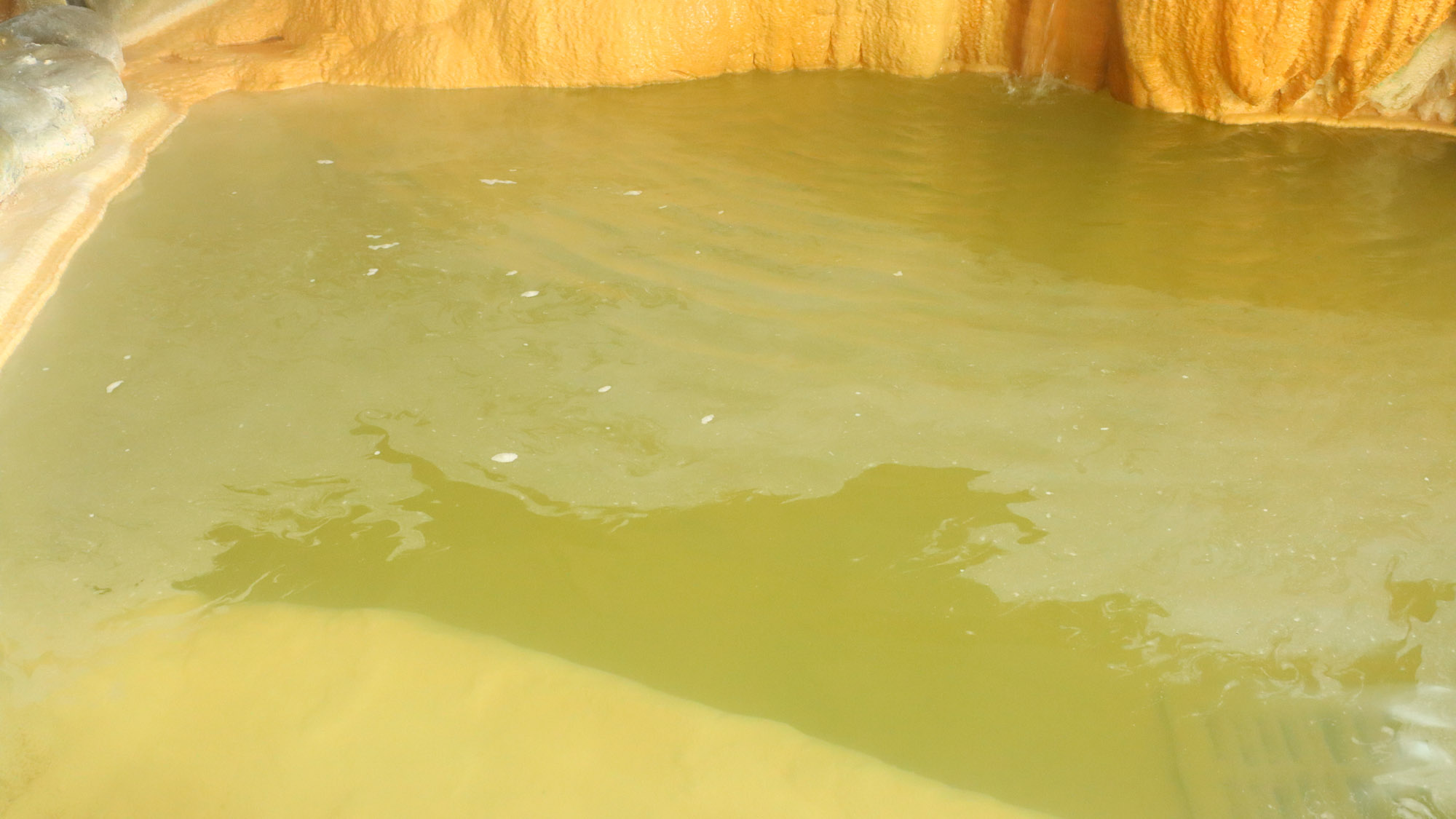 ＜温泉＞美しいエメラルドグリーンのお湯に湯の花が浮いています