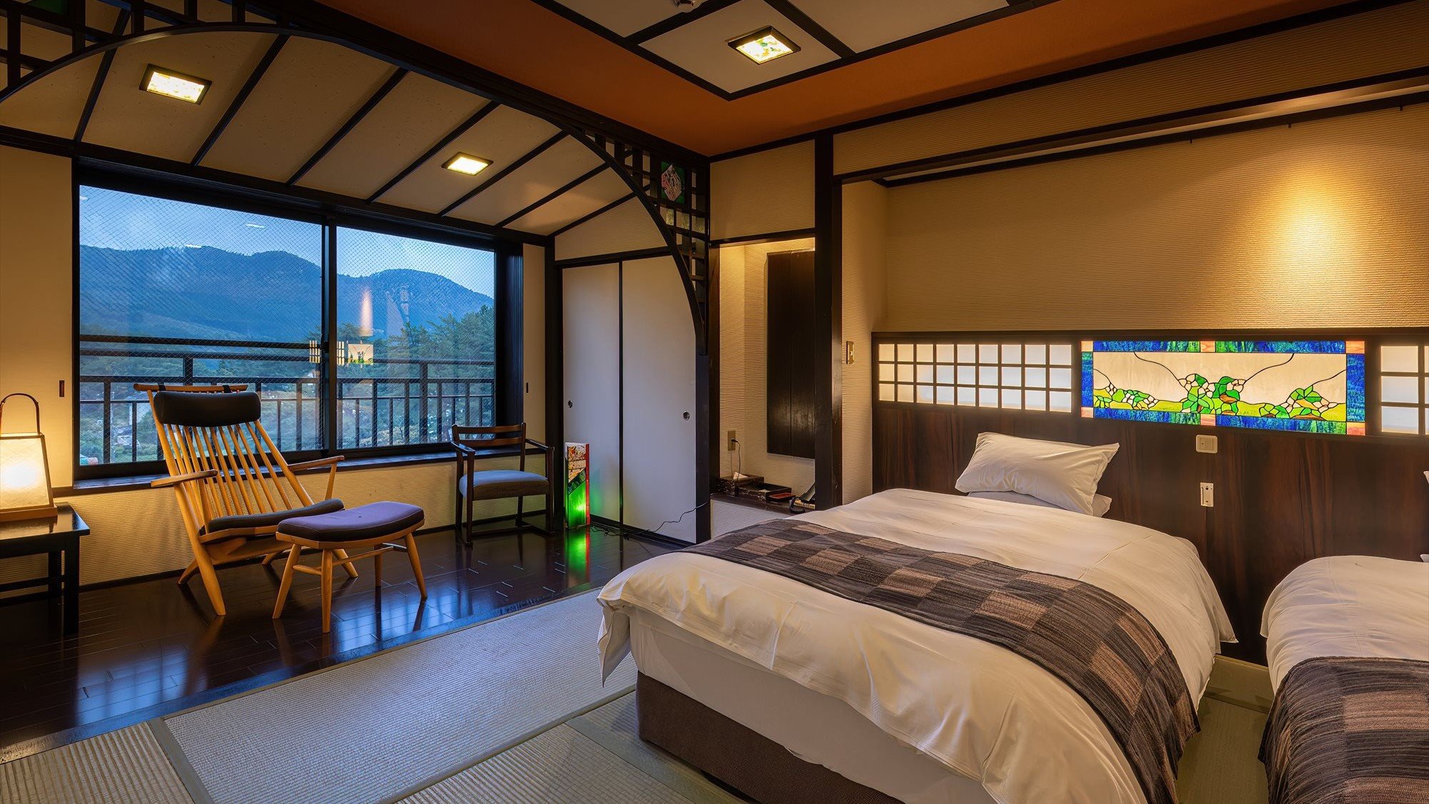 ■「KASHIWA」のデザイナーズチェアで寛ぎながら眺める田沢湖。※客室一例