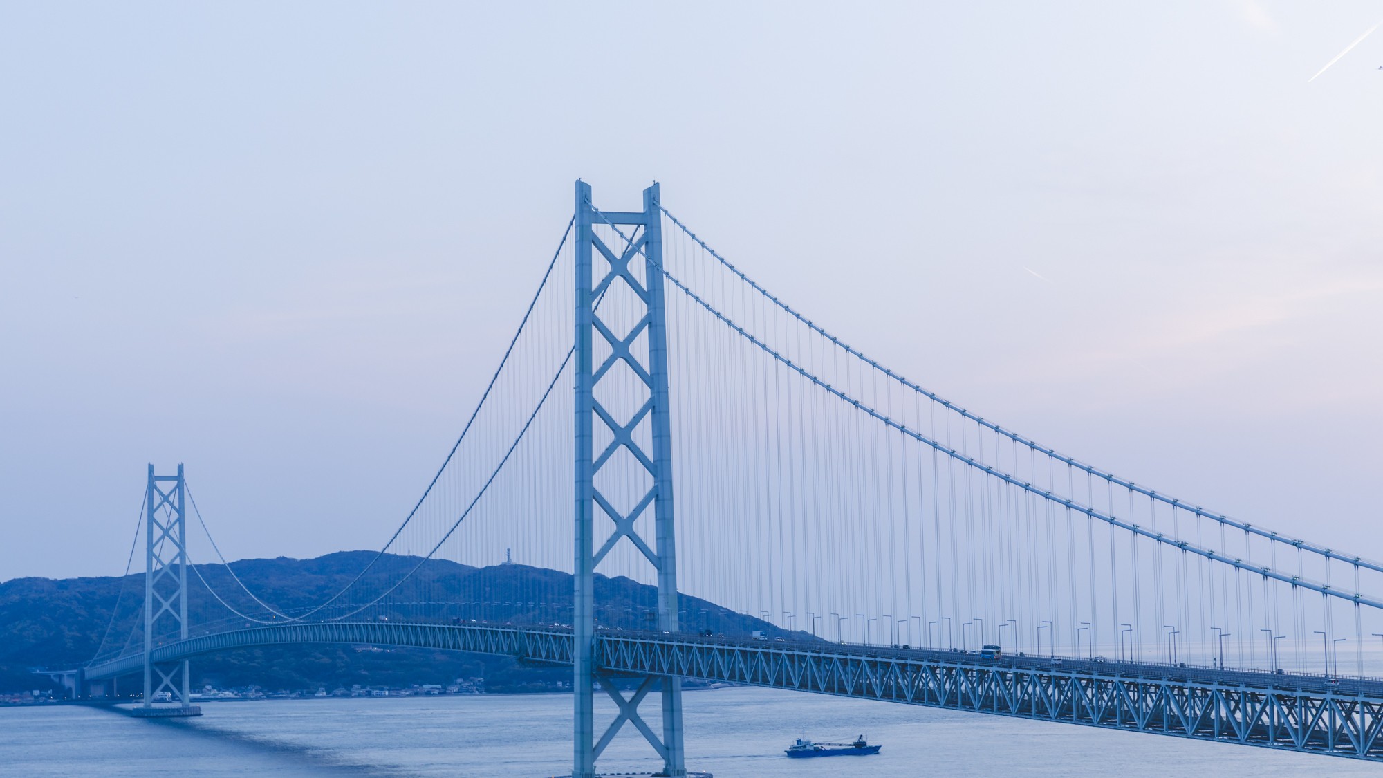 明石海峡大橋の美しいアーチと、どこまでも穏やかに広がる瀬戸内海の光が優しいきらめきで包みこむ