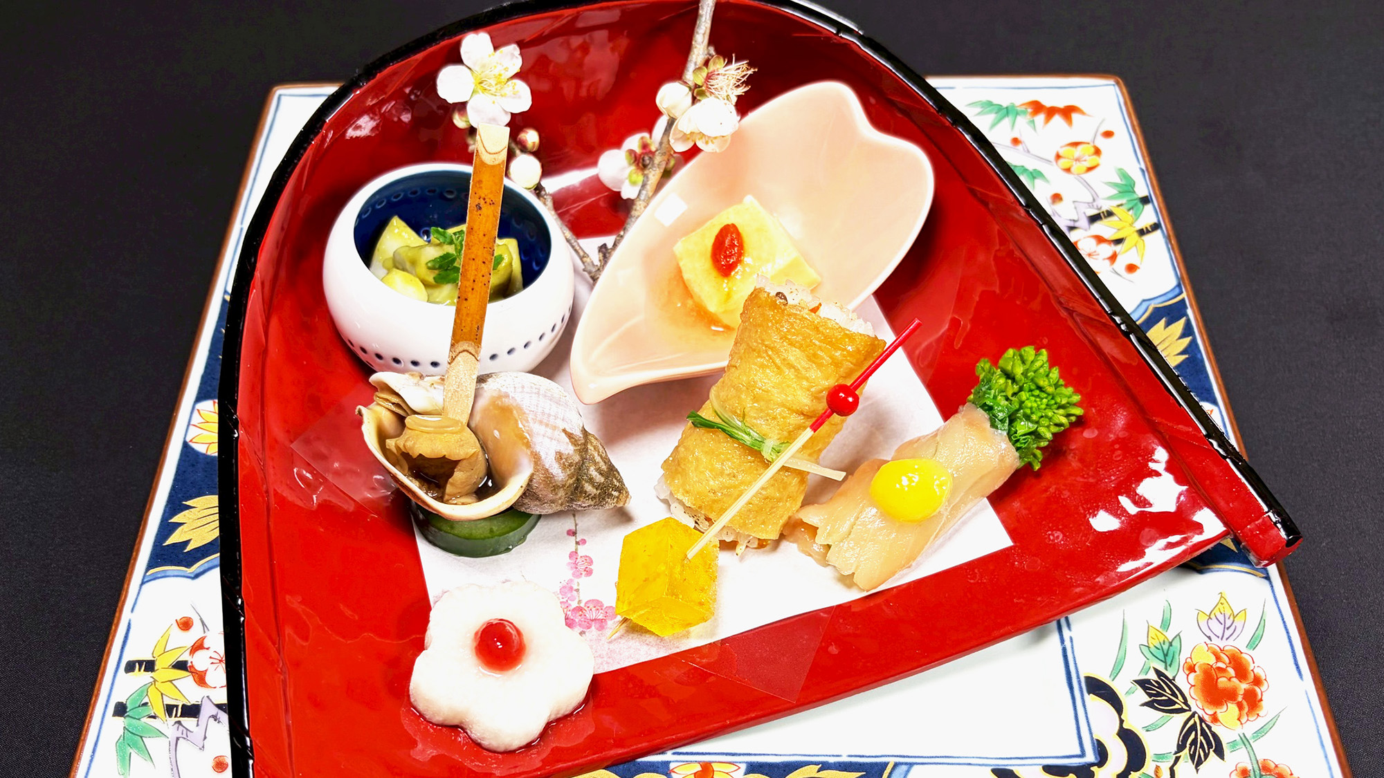 前菜一例：俵いなり、乾酪豆腐、菜の花サーモン、つぶ貝旨煮、金柑の琥珀糖、木の芽和え、梅花長芋甘酢漬け