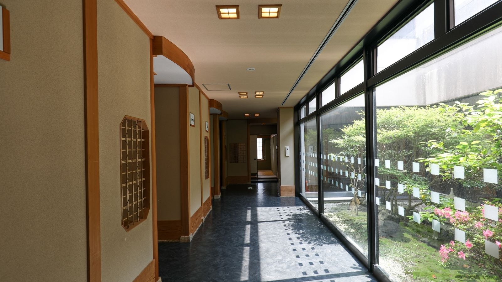 【回廊（中庭沿い）】 ガラス越しに緑を望む和の回廊。移動の時間も癒しのひとときに。