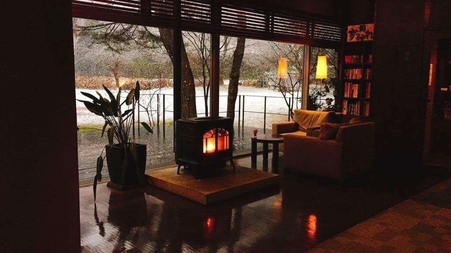 冬のロビーラウンジ／幻想的な雪景色と温かな暖炉の灯り、日常の喧騒から離れた穏やかな時間が流れる
