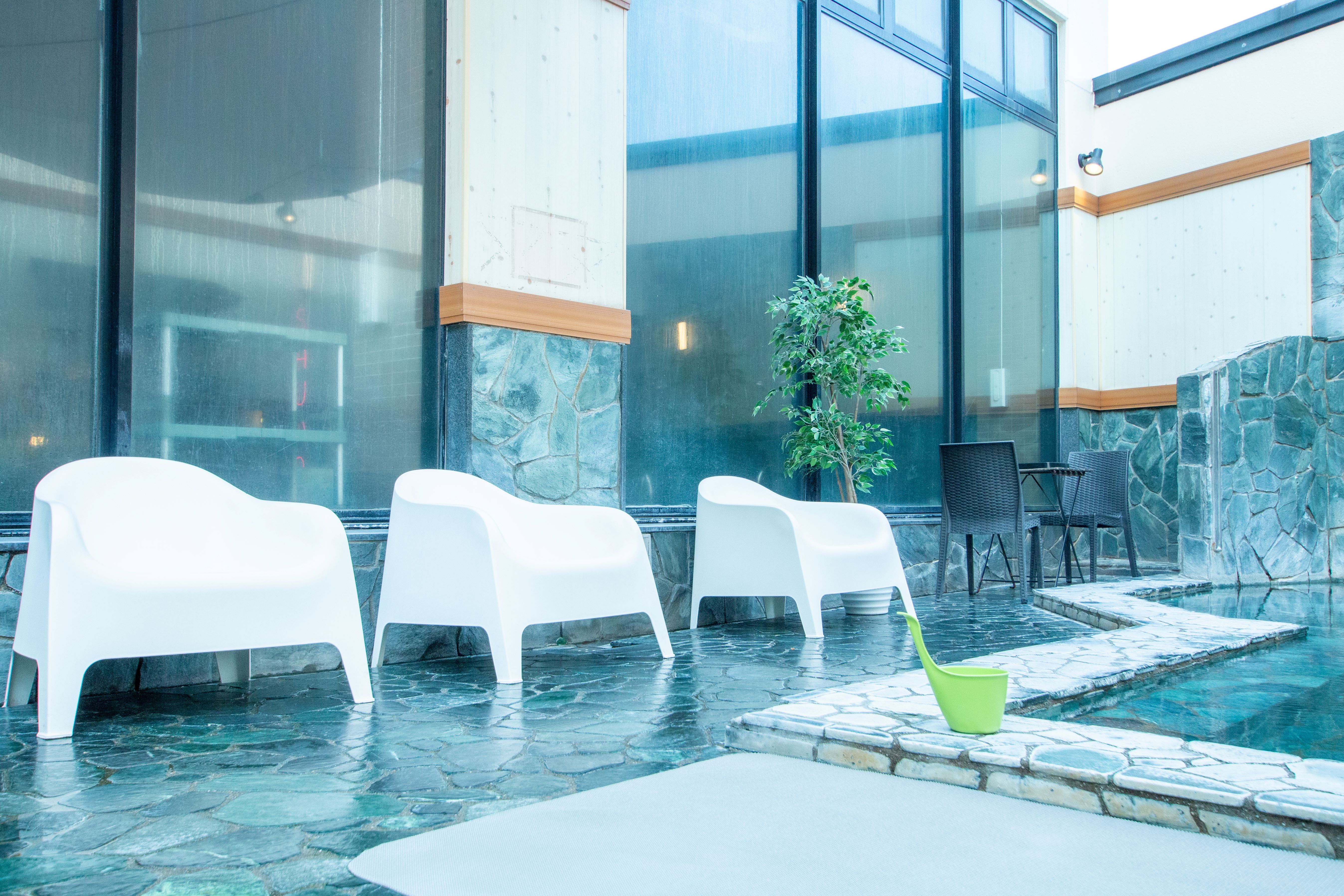 おふろcafe utataneの露天風呂。浅い湯船の中に白い椅子が並んでいる