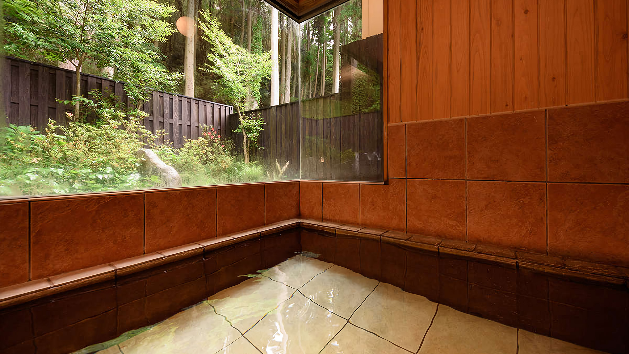 【男性風呂】男湯の内湯から眺める森の佇まいです。100％源泉かけ流しの温泉をお楽しみ下さい。