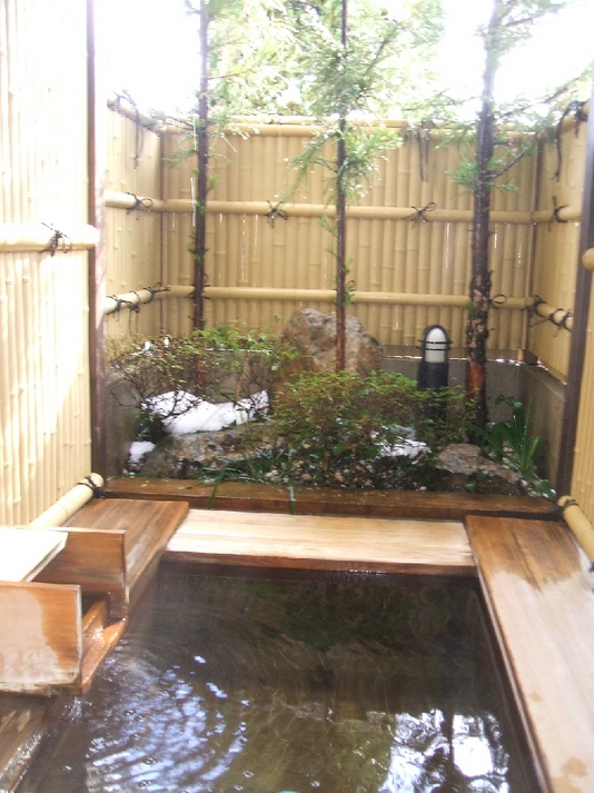 An open-air cypress bath with a snowy view