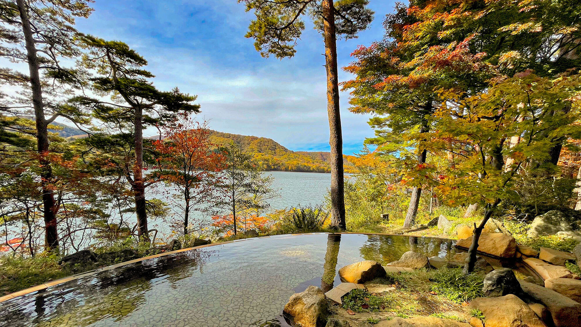 【ひばらみの湯】桧原湖を眼下に望む露天風呂。紅葉で色づいた木々と湖を眺めながらお寛ぎいただけます。
