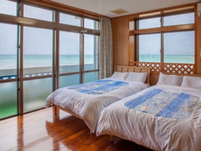 ツインベッドの主賓室からも美しい海が望めます。窓の外は屋嘉ビーチ。