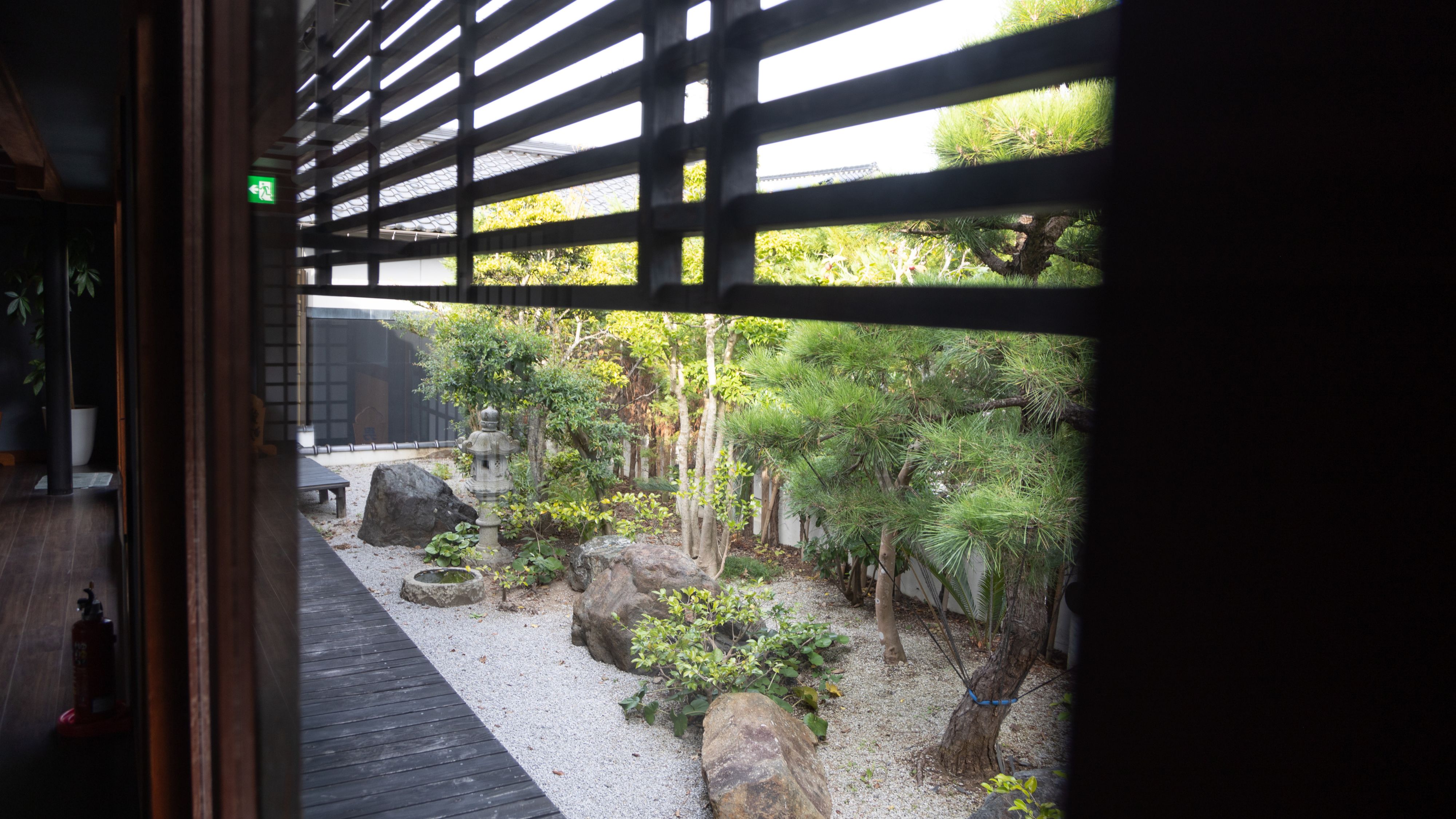 【施設】格子の奥に広がる和風庭園の趣。季節の彩りと静けさが織りなす、癒しの庭景。