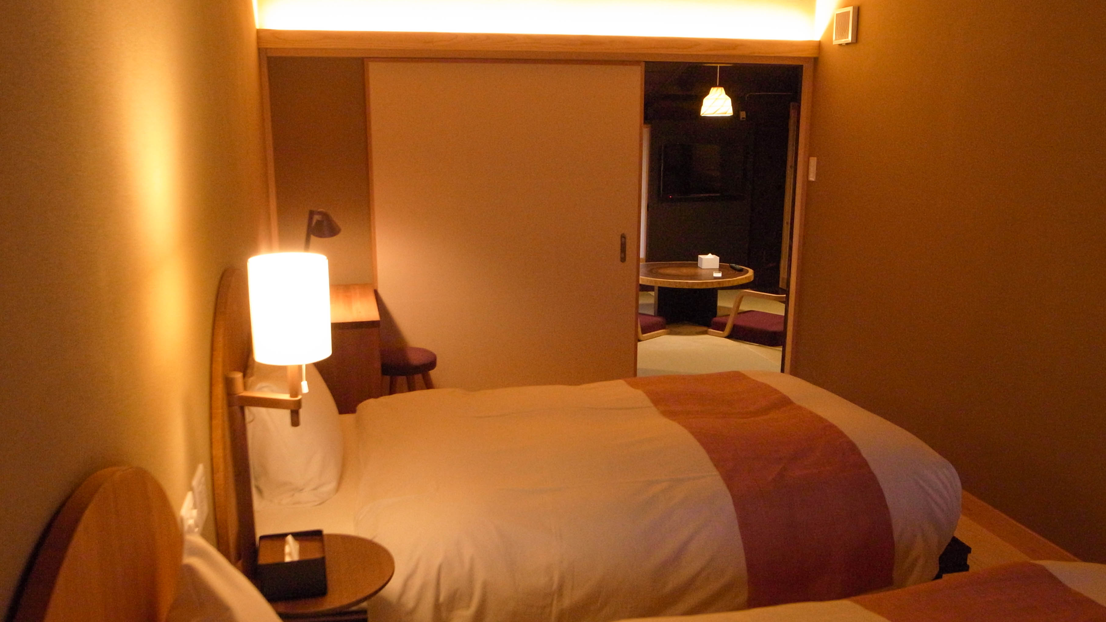 ＜ベンガラの間＞ベッドルームから和室（リビング）方向を。柔らかい間接照明で満たされています。