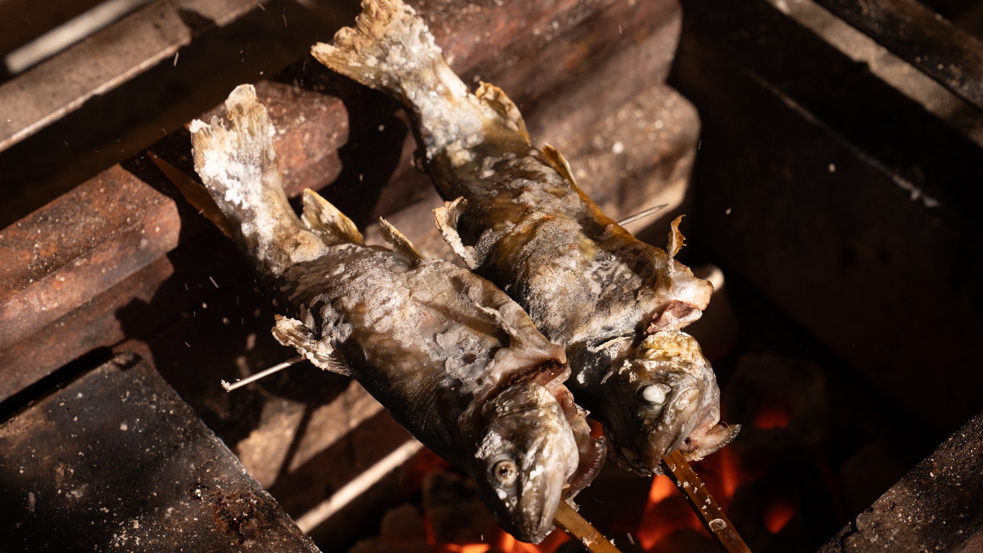銭がめの囲炉裏。炭火に串を立てて川魚を焼いているところ
