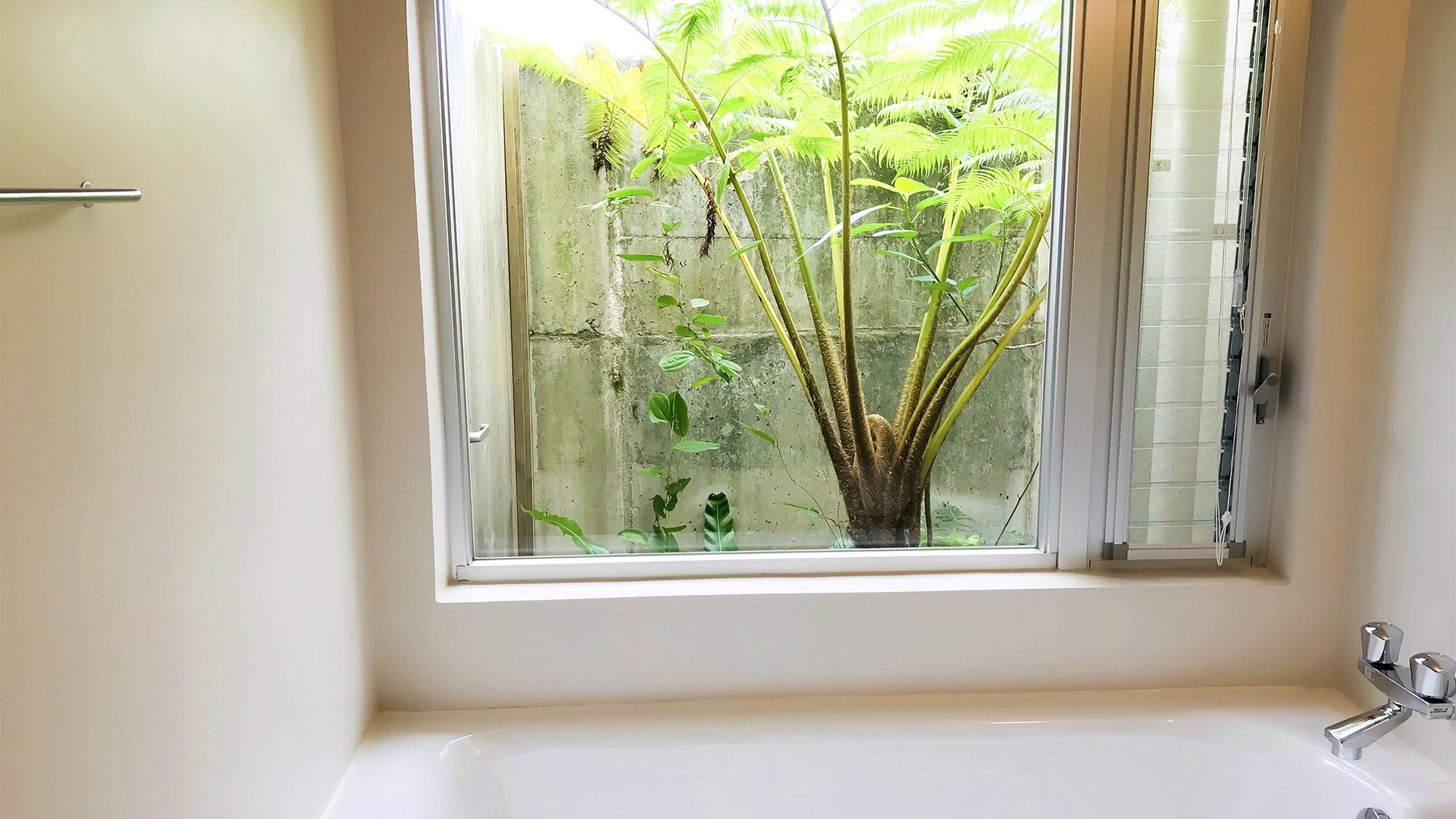・大きな窓のある白を基調とした清潔感のあるバスルーム