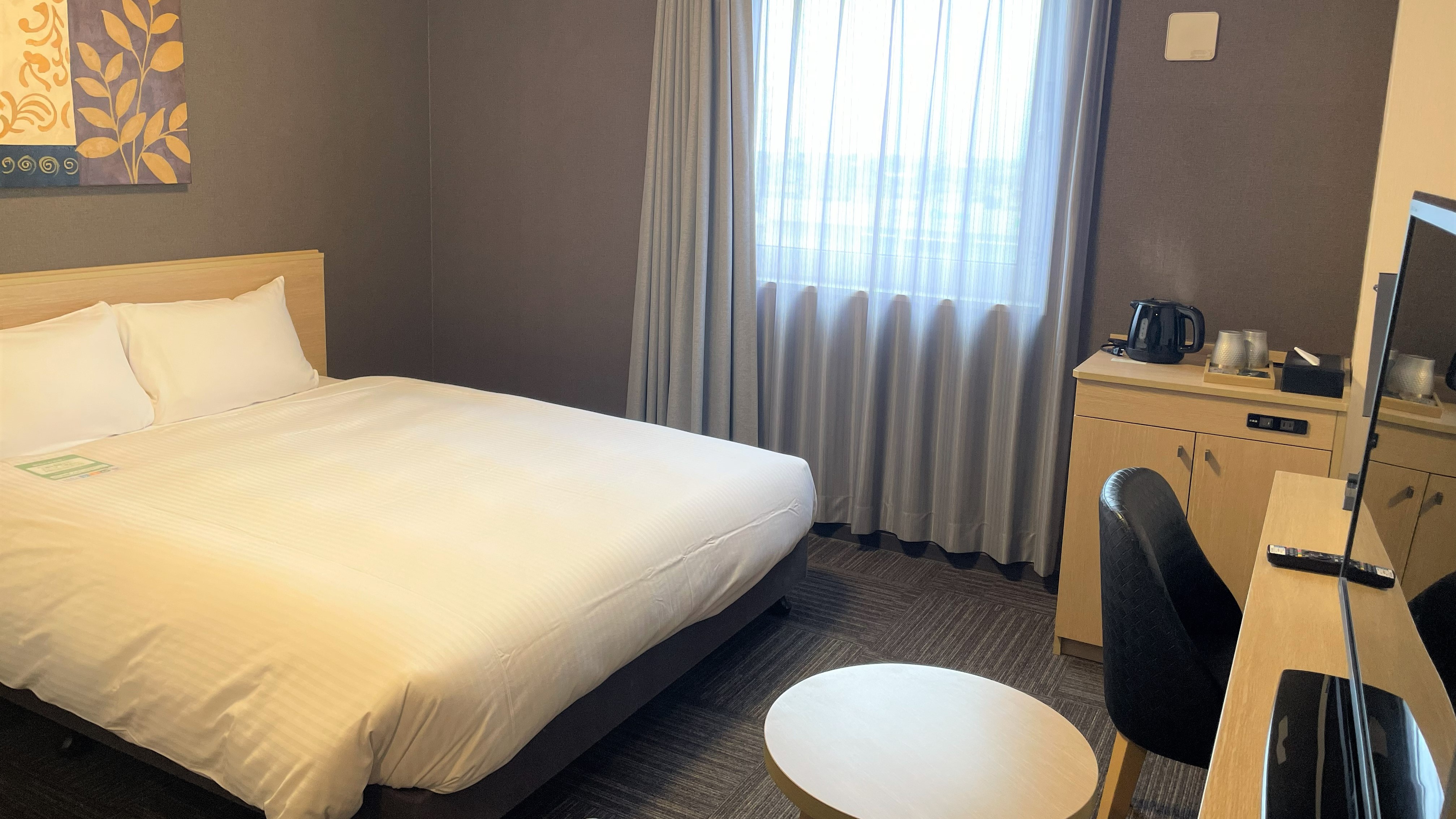 18㎡の部屋に160cm幅のベッドを設置しております。デスクの他に丸テーブル台、椅子2脚をご用意しております。