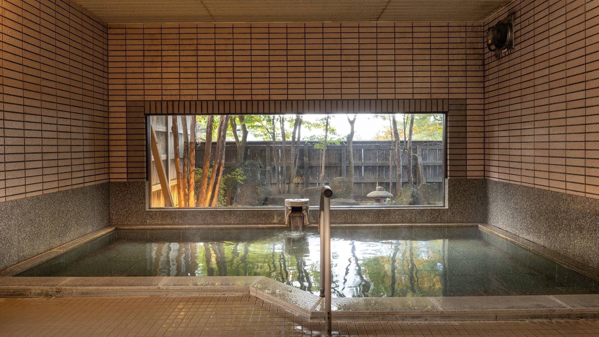 ■大浴場｜ガラス越しに自然木を植え込んだ庭園を 楽しみながらご入浴できます。