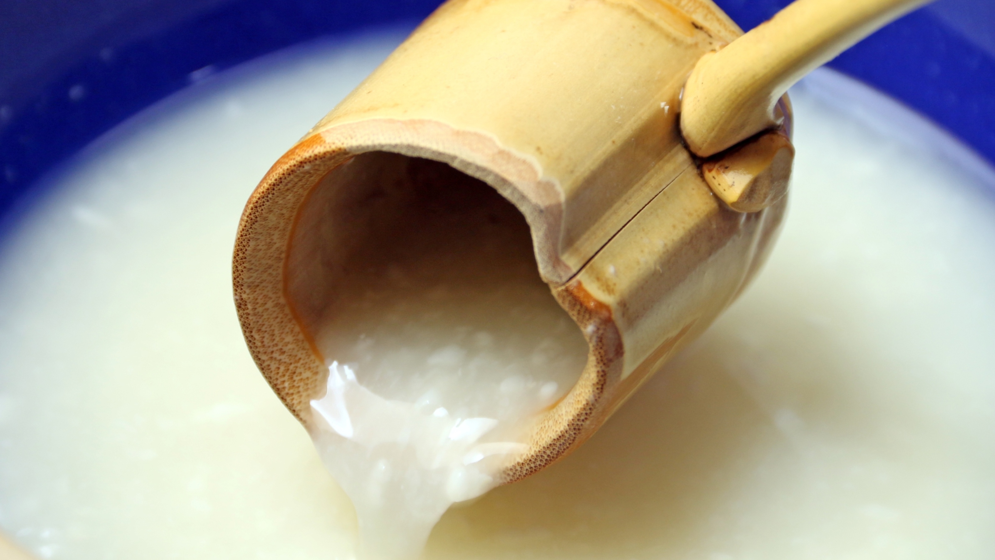 獅子吼荘の自家製どぶろく。竹筒から白いどぶろくを器に注いでいるところ