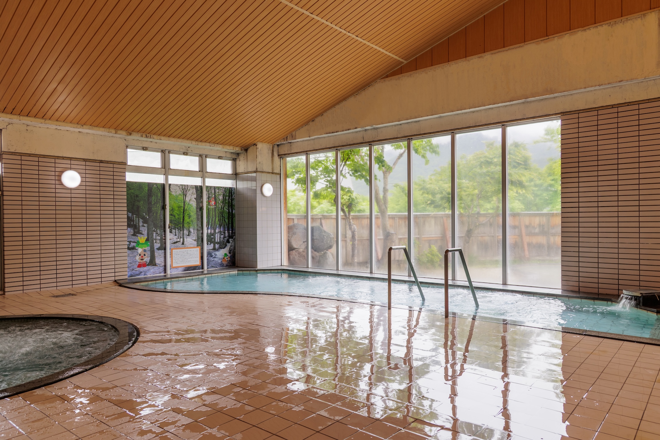 大きな窓ガラスからは只見の美しい自然を眺められる大浴場。たっぷりと温泉が溢れる