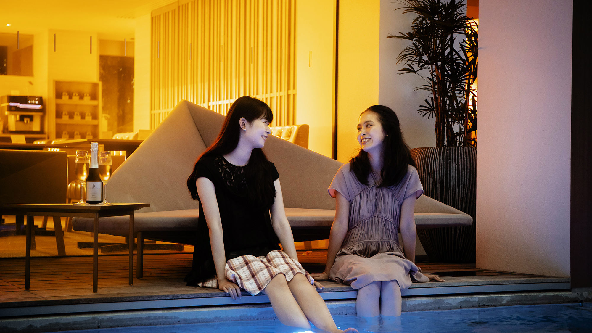 【屋外温水プール】 幻想的な輝きを放つ夜のプール。足を浸けて会話を愉しむお客様の姿も。