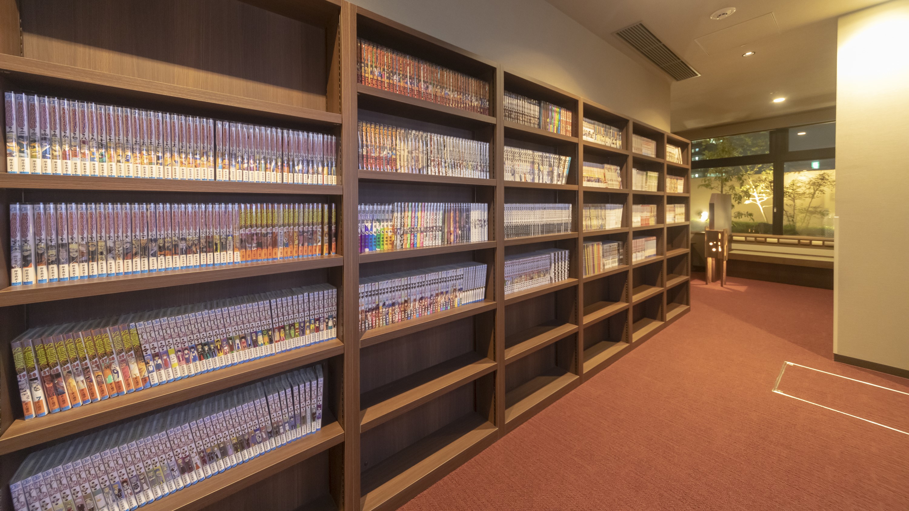 ドーミーインPREMIUM大阪北浜の湯上がり処にあるドーミー文庫。壁一面の本棚に漫画が並ぶ