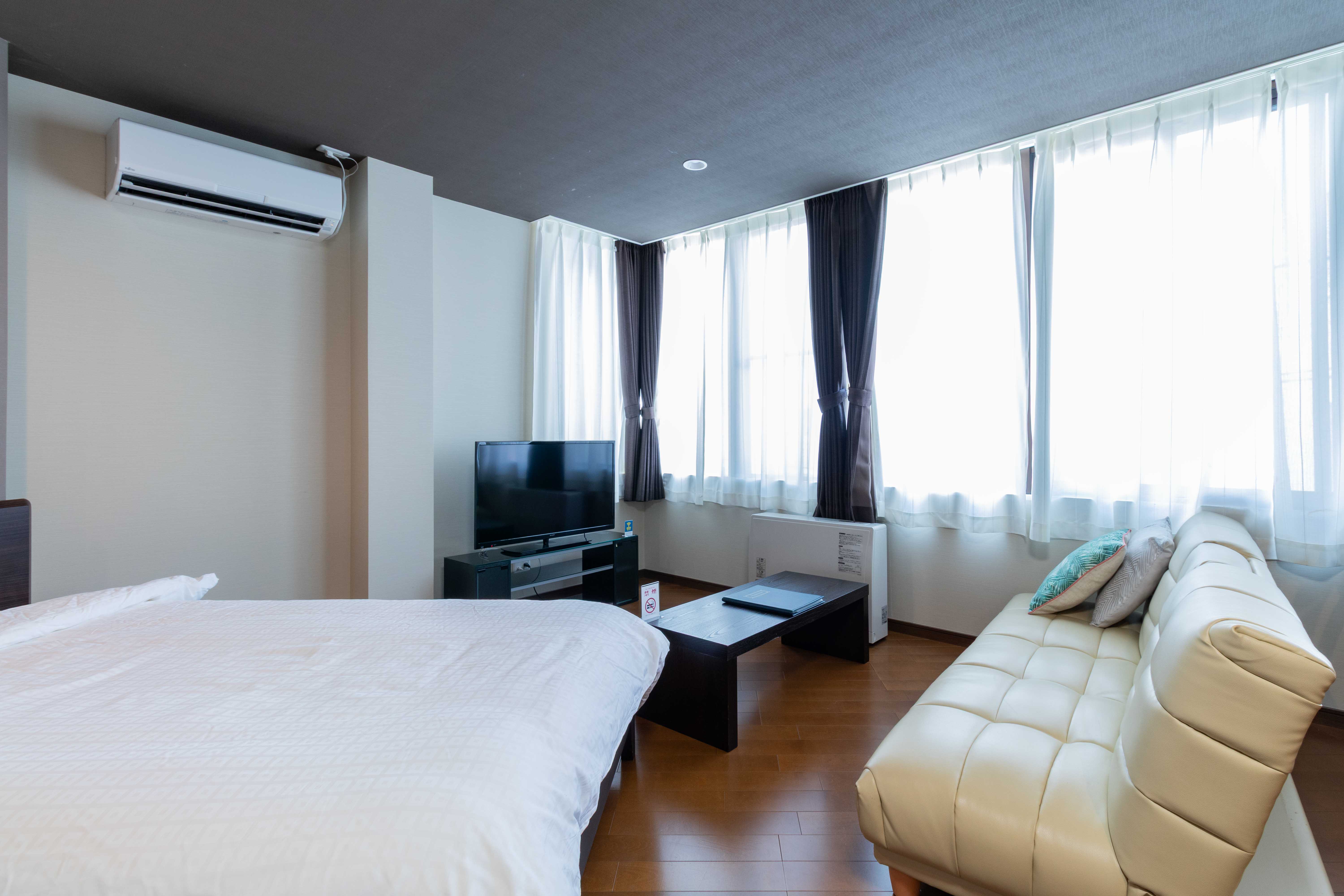 【ツイン/室内】大きな窓から光が差し込む明るい客室。ソファでゆったりと寛げます。