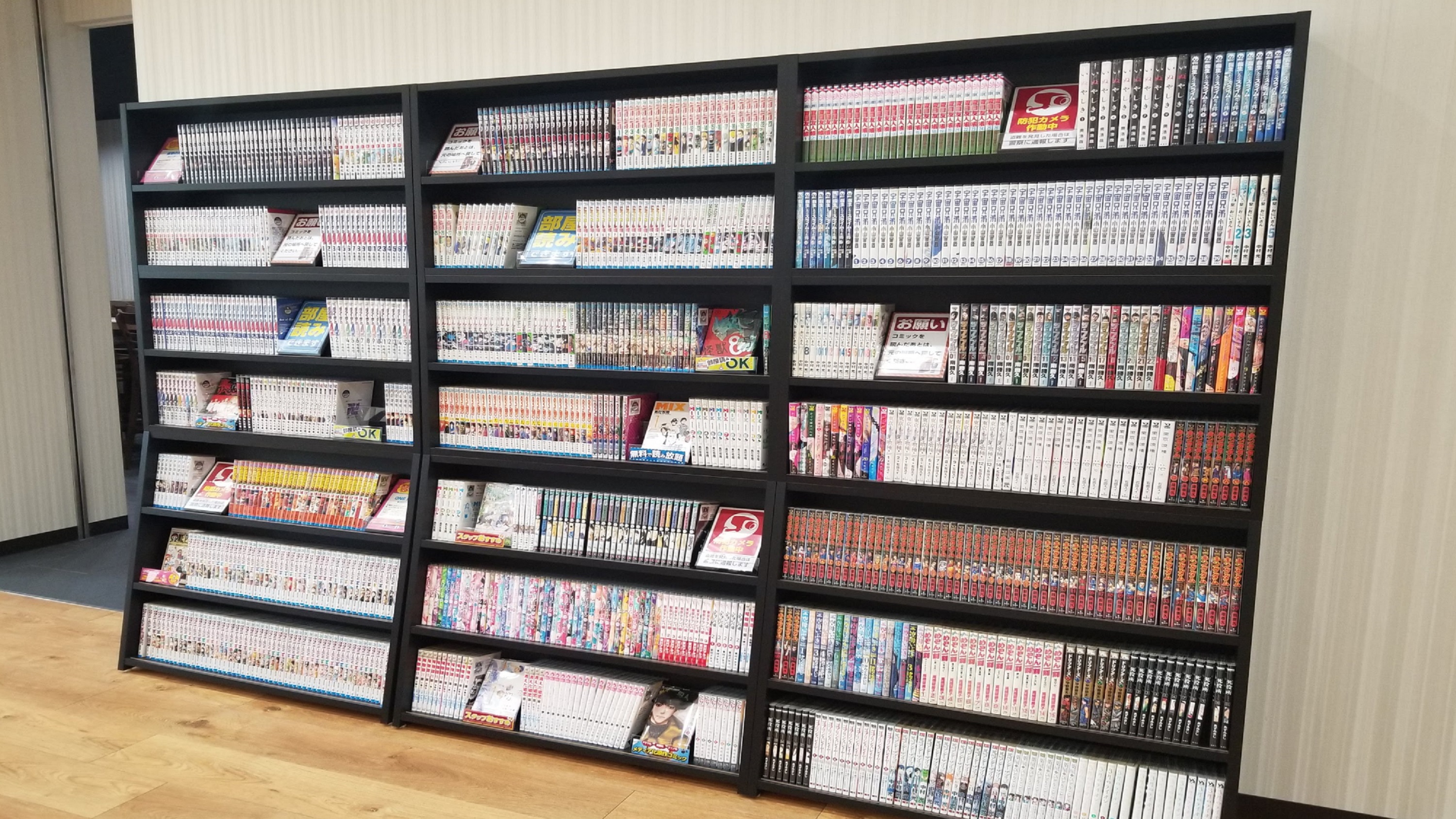 変なホテルプレミア東京 浅草田原町の2階のマンガコーナー。黒い本棚に漫画の単行本が並んでいる