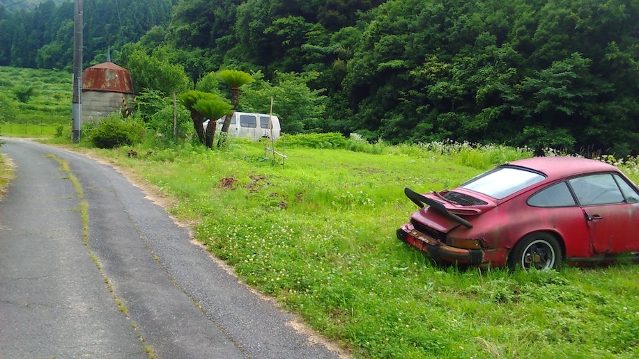 右手に赤いポルシェの廃車が見えたら、車で1分