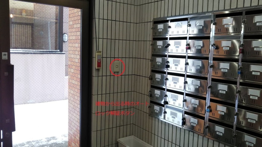 マンション1階内部(銀色のメールボックス内に部屋の鍵あります。オートロック解錠ボタンはドア右側の白色