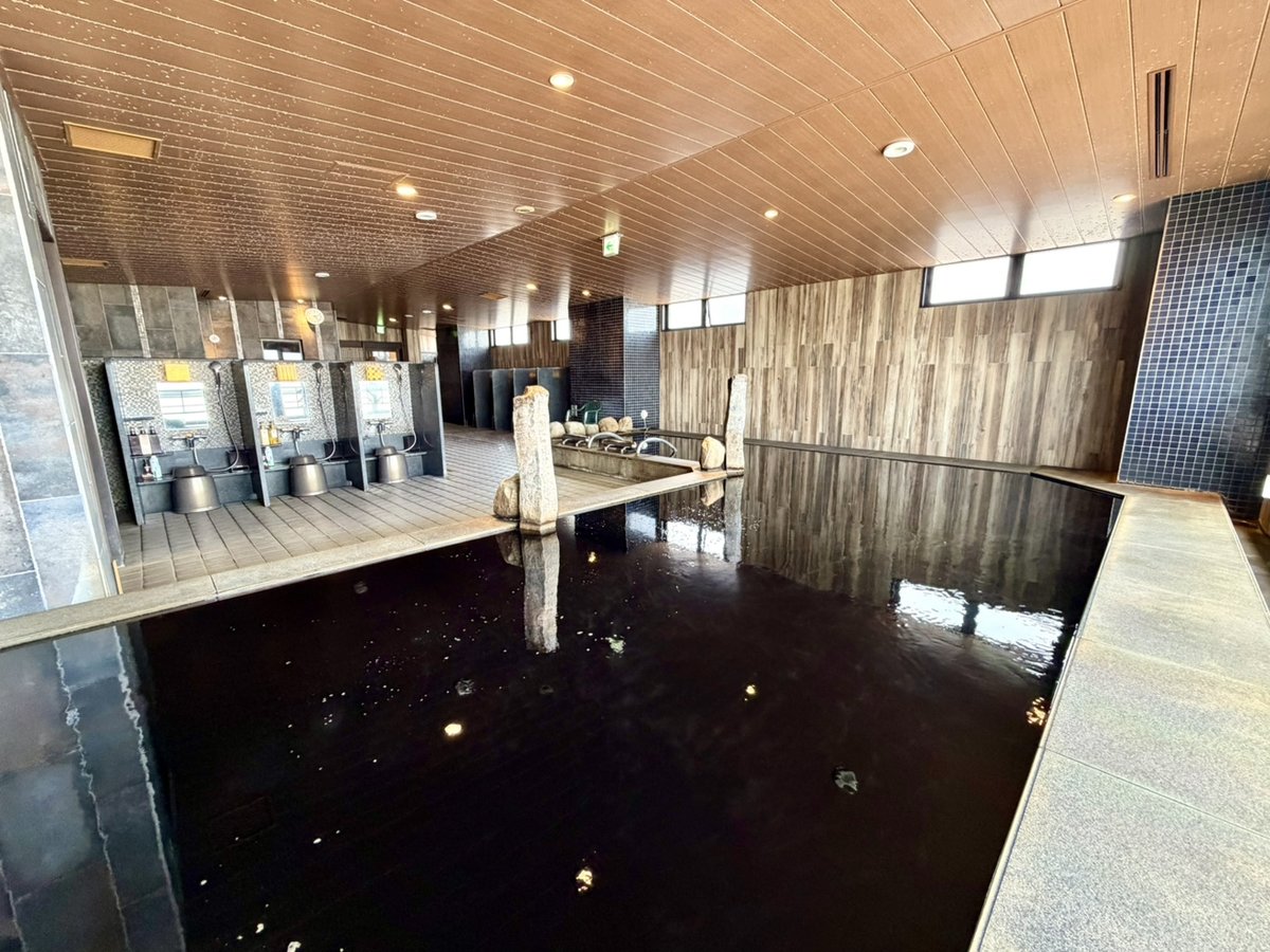 ドーミーイン川崎の男性大浴場の内湯。黒いお湯をたたえた湯船と、木の天井