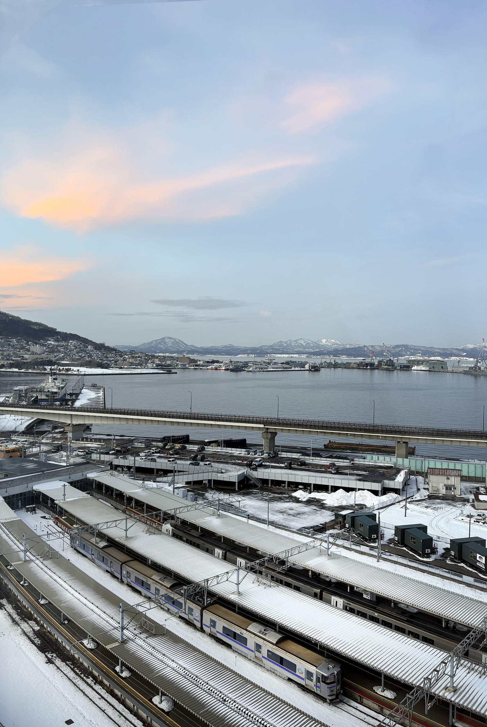 トレイン＆オーシャンビュールーム＜宙船＞の窓から見下ろす函館駅と函館湾