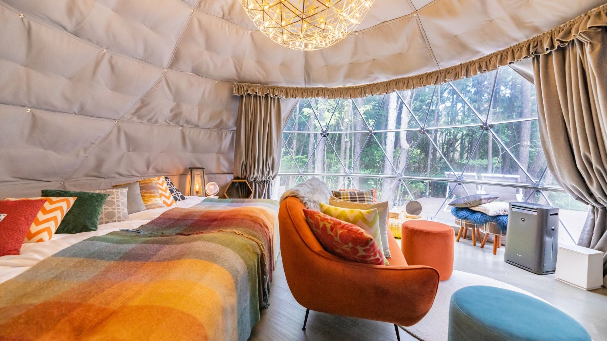 鮮やかなオレンジのソファがアクセント。森の緑と調和する、絵本のような可愛いドーム。