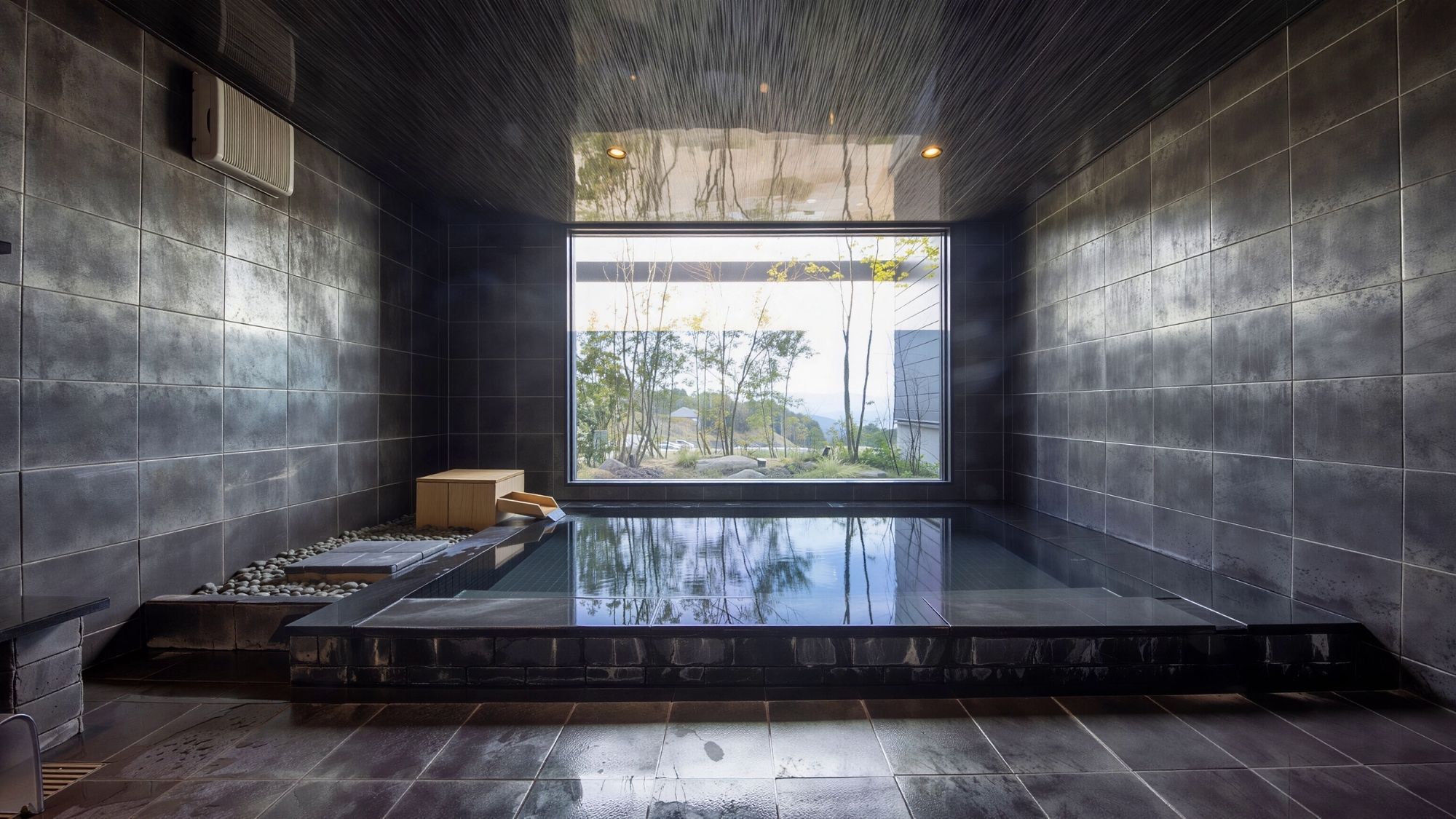 大きなガラス窓が切り取る四季の風景。静寂に包まれた大浴場で、旅の疲れを心地よくリセット。