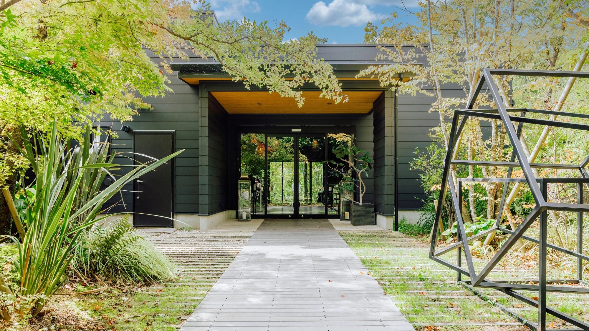 木の温もりとモダンな黒。森の緑に映えるスタイリッシュな母屋がお出迎え。