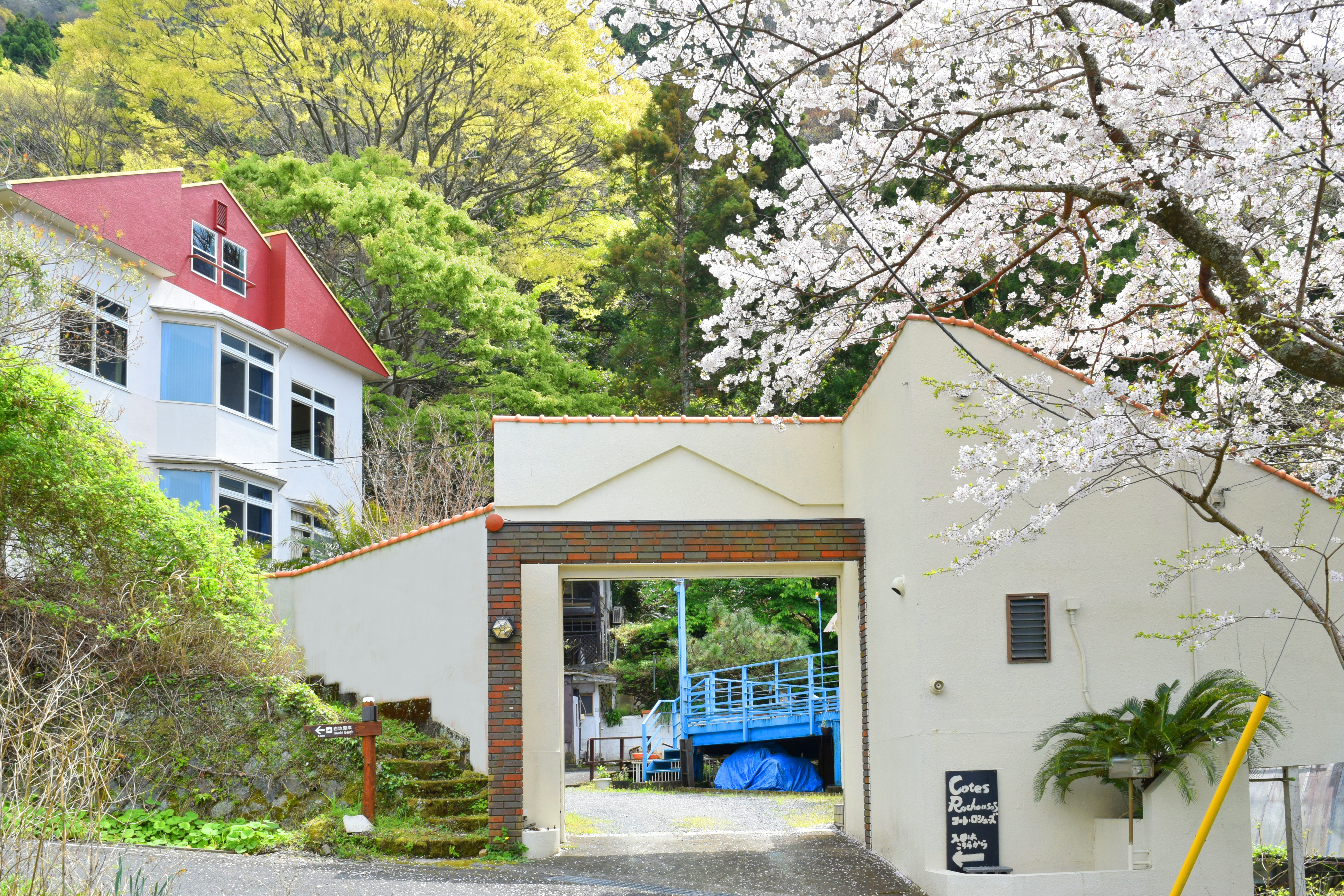 緑の木々の中に立つ3階建ての三角屋根の本館と別棟山荘。全室広々20平米以上でオーシャンビュー