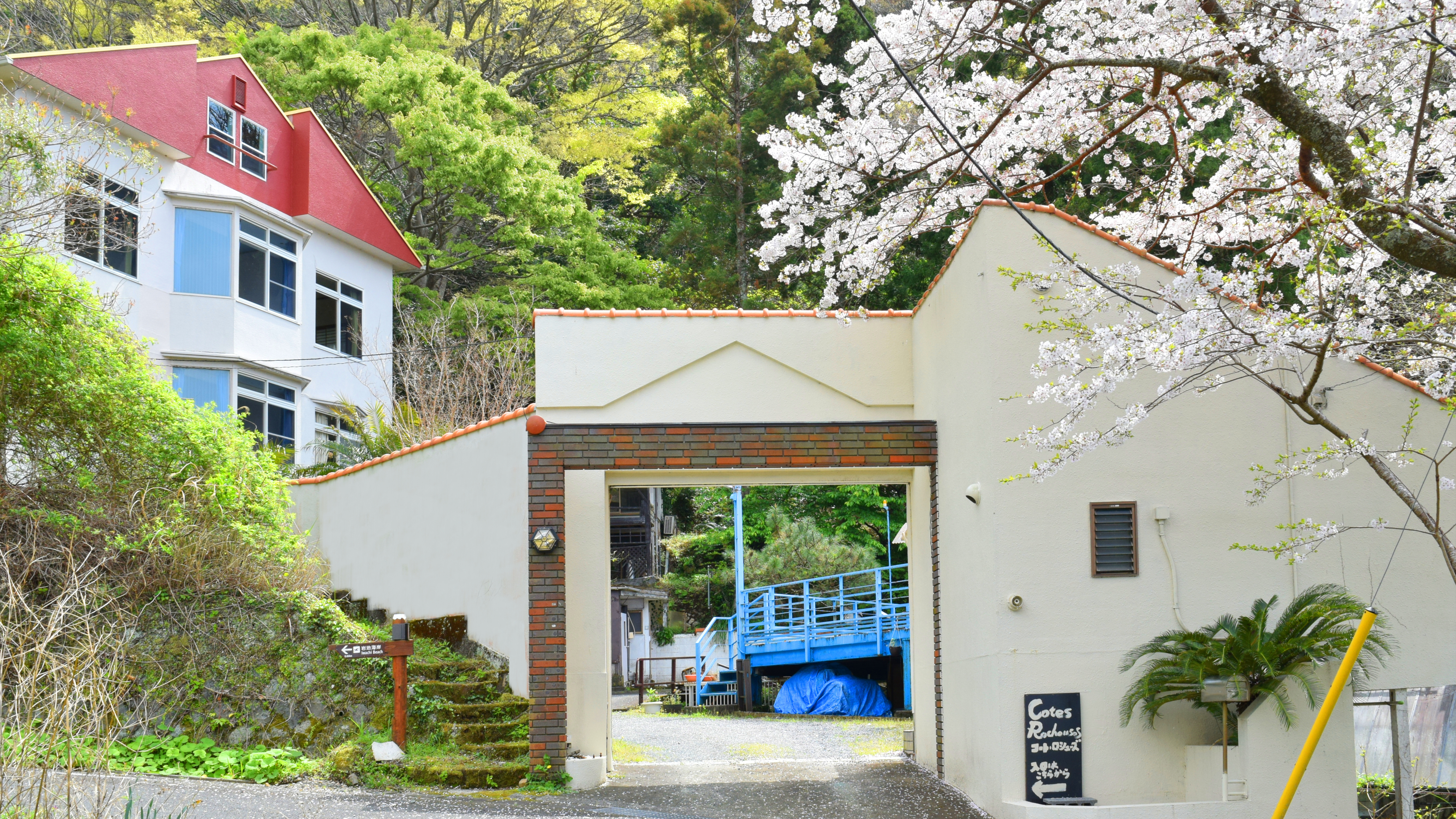 緑の木々の中に立つ3階建ての三角屋根の本館と別棟山荘。全室広々20平米以上でオーシャンビュー