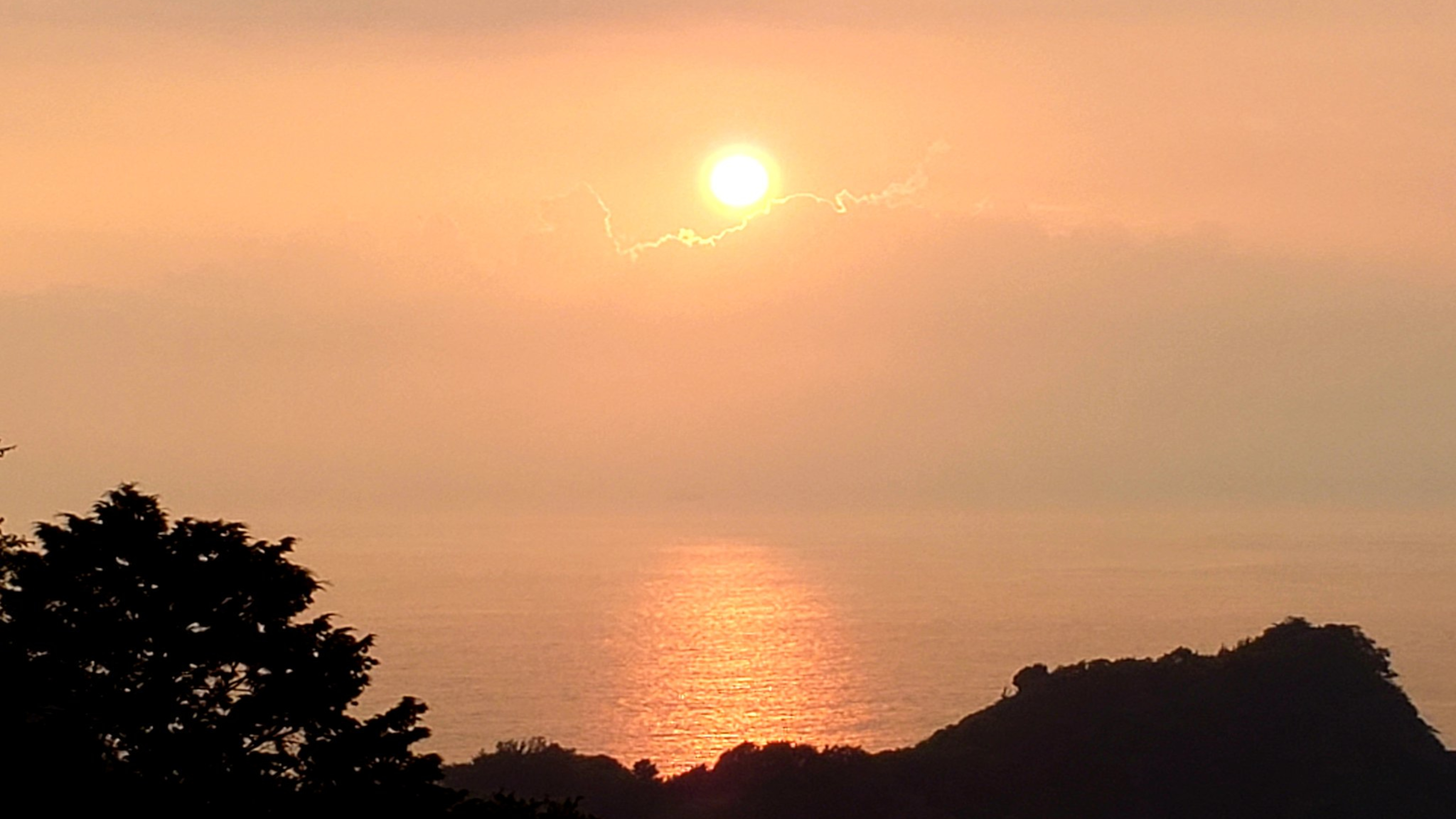 黄昏に染まる空の下　海に夕陽の道が続く