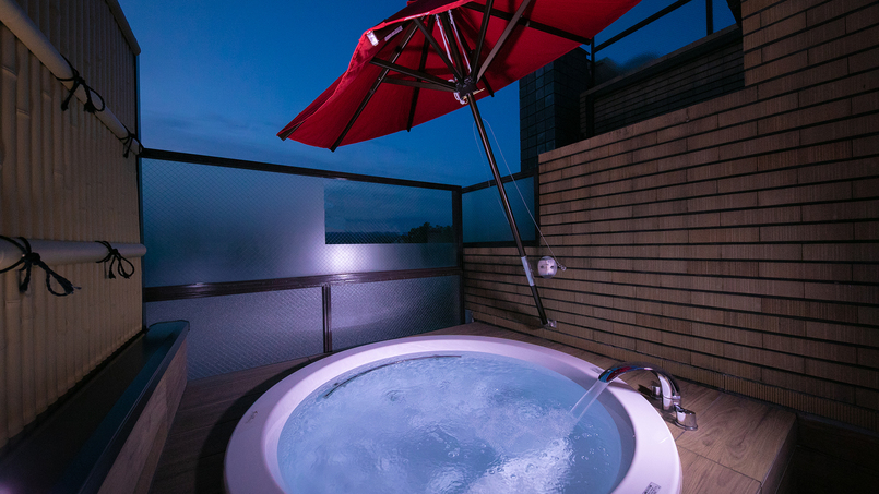 《デラックスツインA》当館唯一の露天風呂。赤い野点傘付きの大きなバスタブでゆっくりとお寛ぎください。