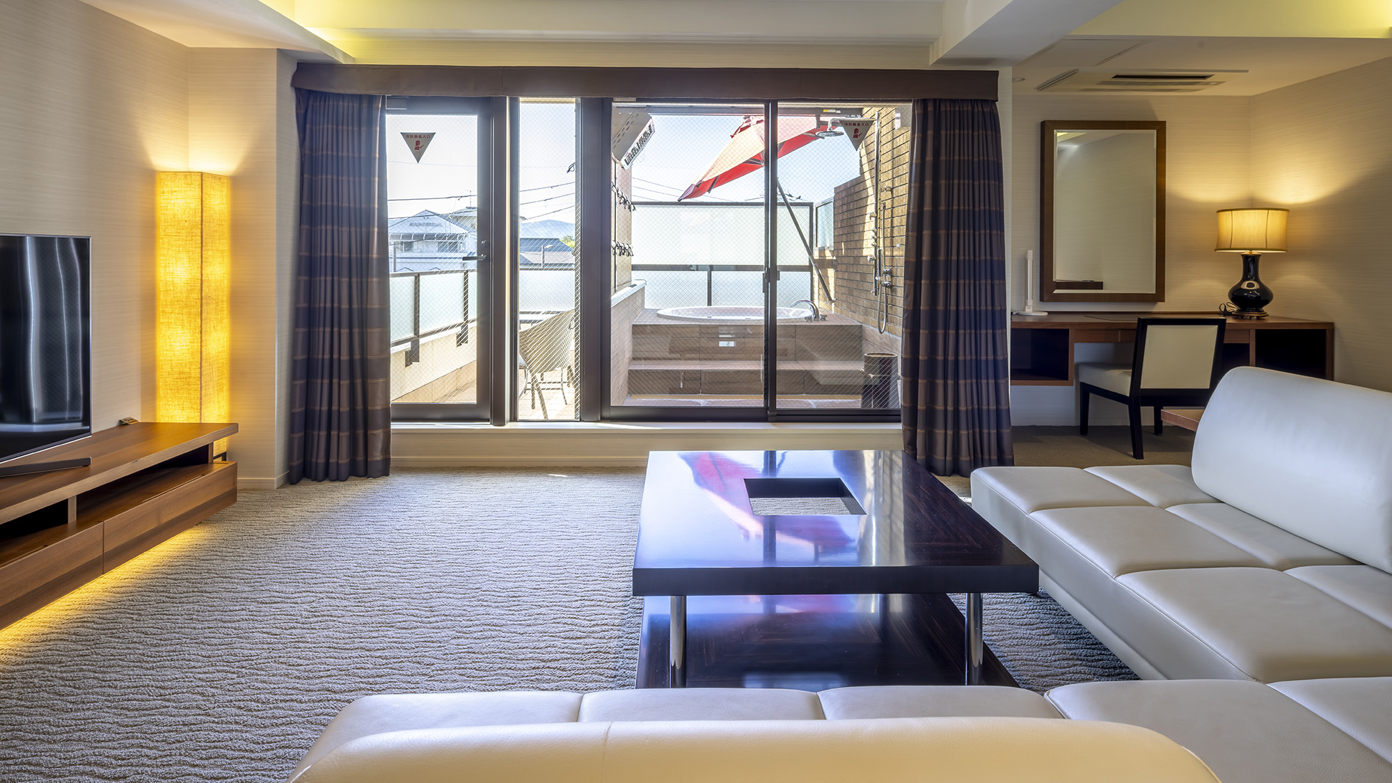 《デラックスツインA》モダンでシックなコーナーソファーが配置された広々したリビング。