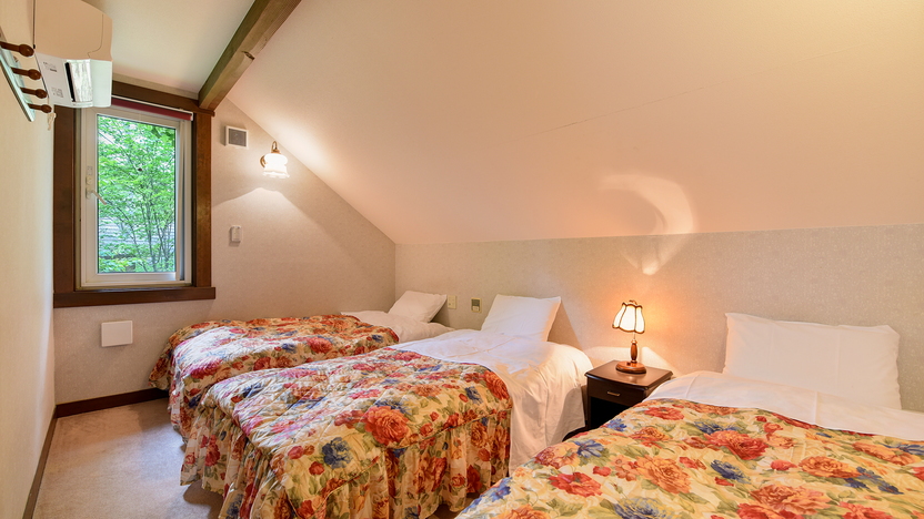 *部屋一例（コテージタイプ1）／寝室は2部屋、こちらはシングルベッド3台ございます。