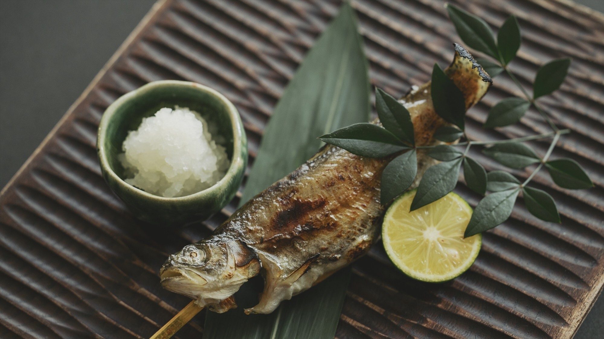 【お食事処／夕食一例】日本古来から伝わる原始焼きで虹鱒をご提供いたします。