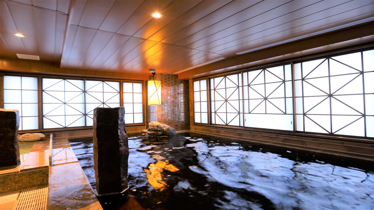 ドーミーイン池袋の大浴場の内湯。黒っぽいお湯の湯船と、格子の窓