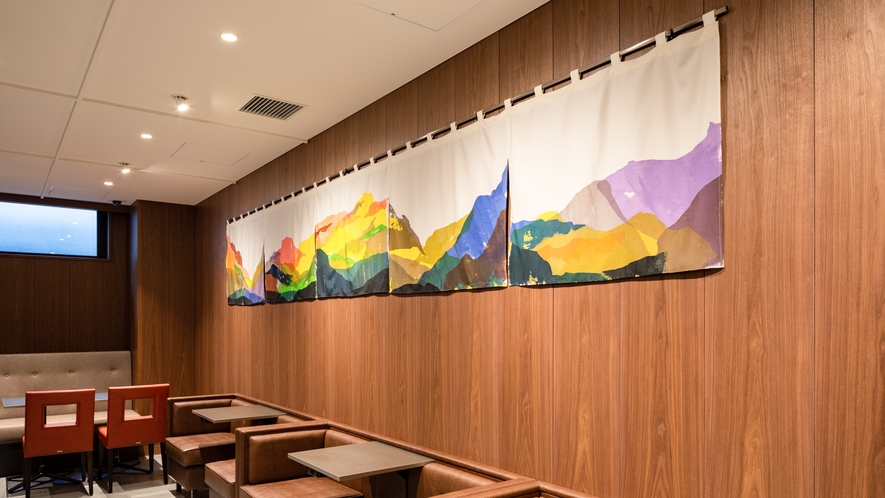 京都の山に囲まれた景観を5枚の生地と様々な色で重ねて表現した「ケイコロール」の暖簾アートを展示