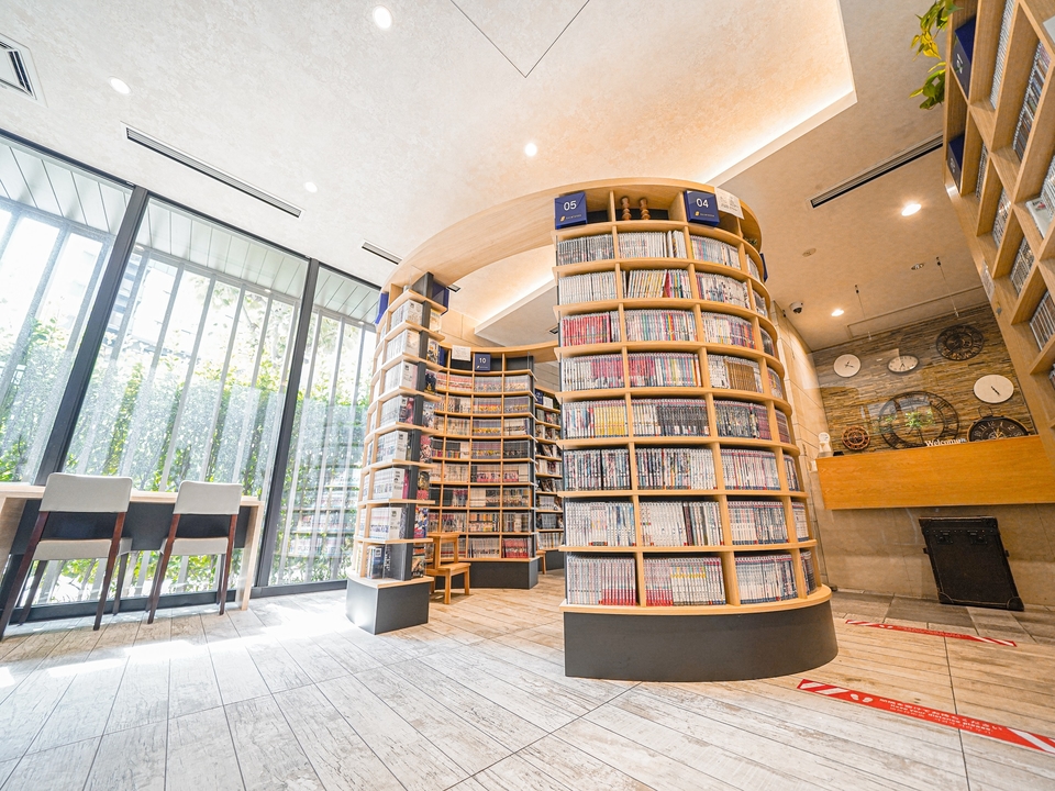 クインテッサホテル東京羽田のMANGA LIBRARY。窓ぎわに丸い本棚が立ち、漫画の単行本がぎっしり並んでいる