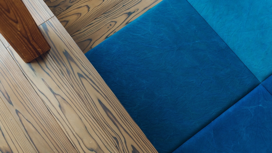 【スイートルーム　点線】リビングの床に、藍染のクッションタイルを敷きつめた特長ある客室