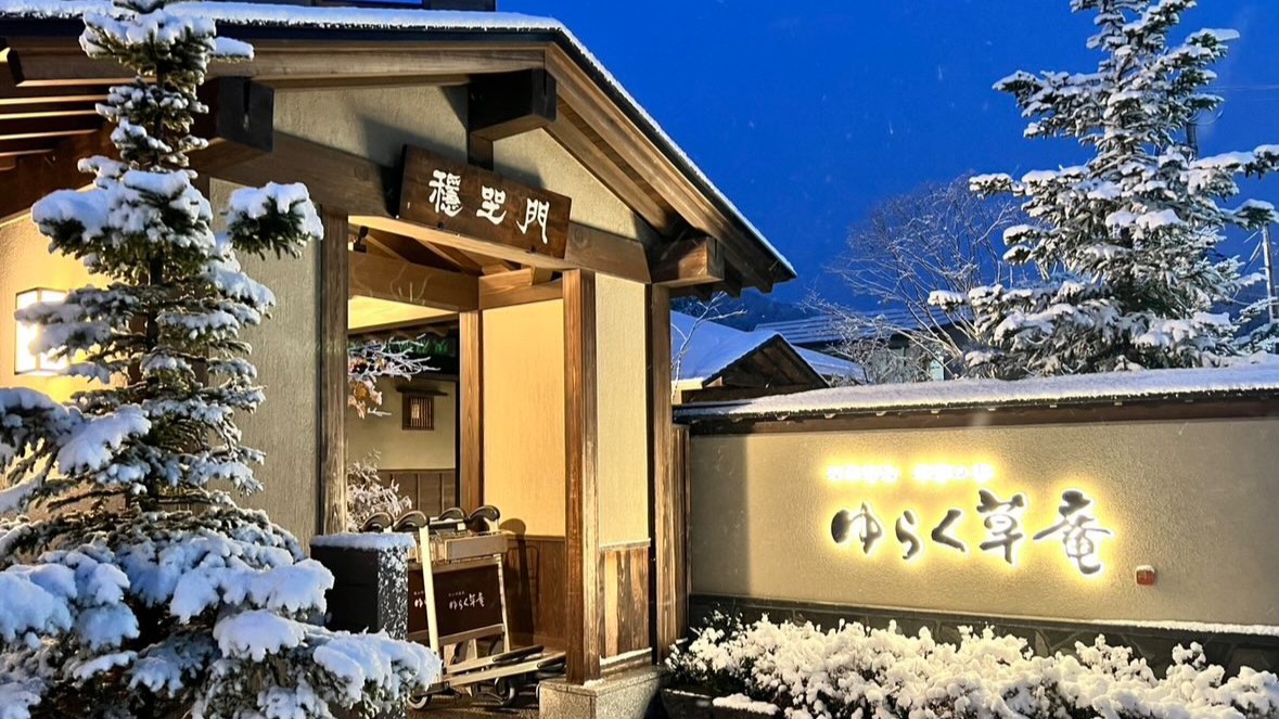 【冬の外観】雪景色の中でやさしく灯る、定山渓ゆらく草庵のサイン。