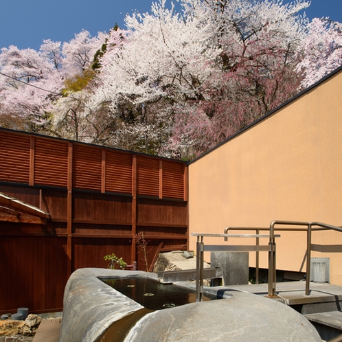 【東湯・露天風呂】桜も絶景！一段高い「原石風呂」で花見の湯あみを