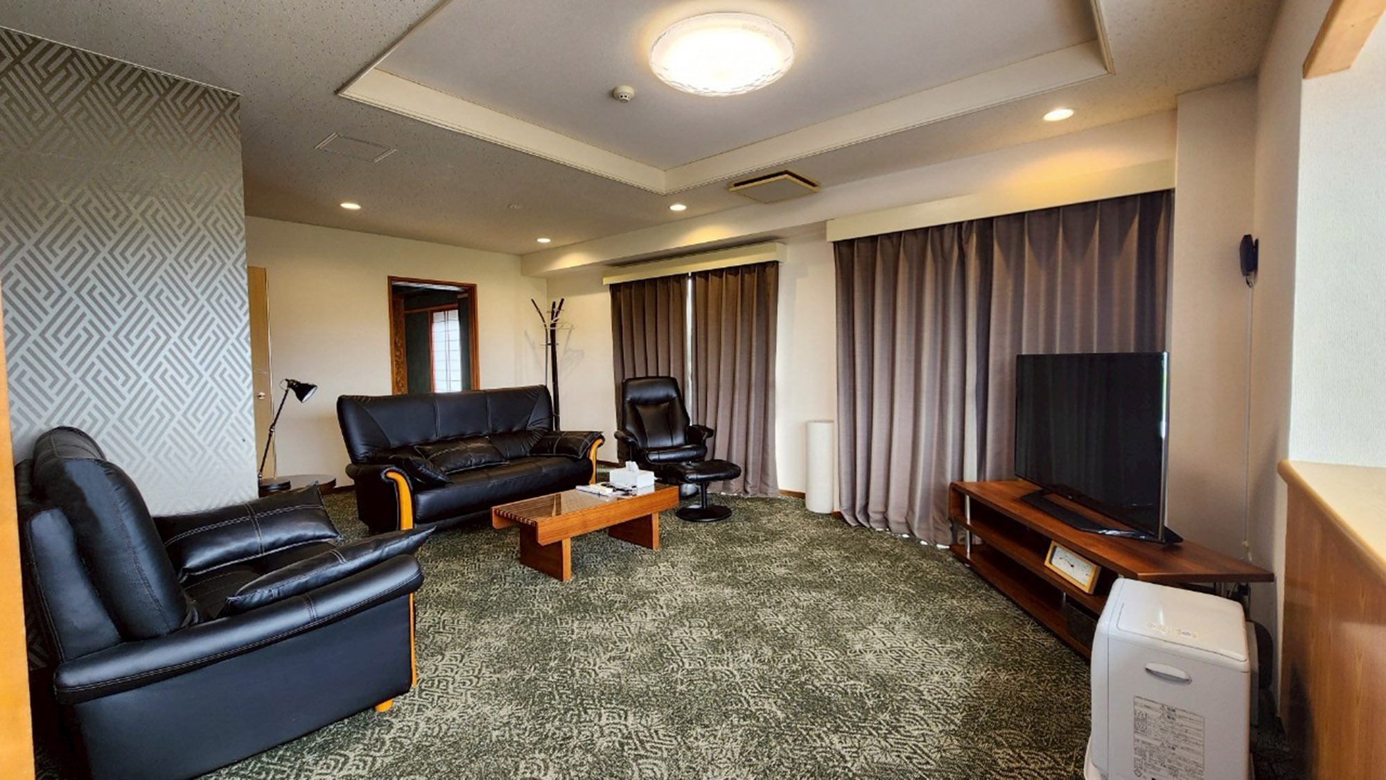 ・【1001：リビング】重厚感のあるソファと大きなテレビを設置。ゆったりお寛ぎいただけます